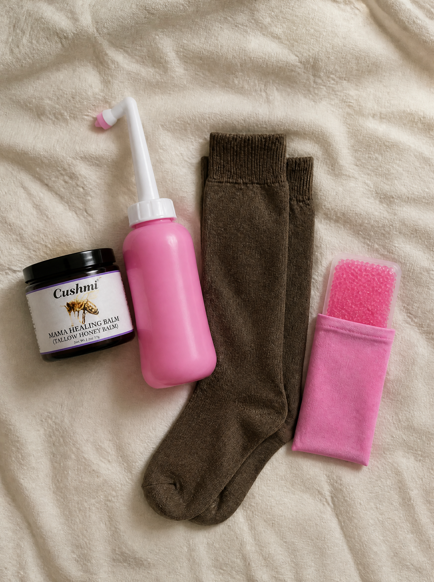 The Cushmi Kit overhead — balm jar, peri bottle, compression socks, cooling pad
